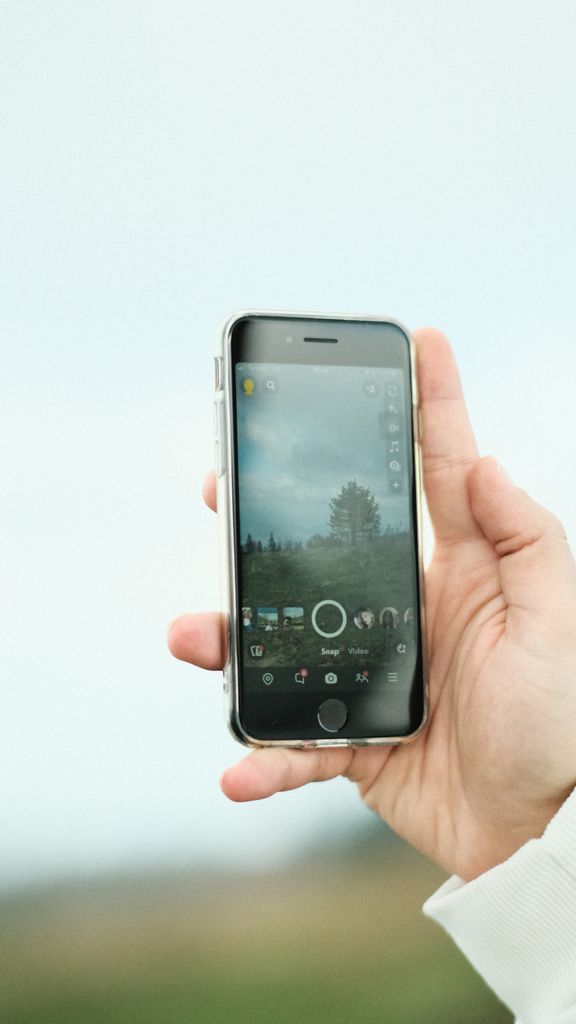 A hand holding a smartphone displaying a photo app screen outdoors in Istanbul, Türkiye.