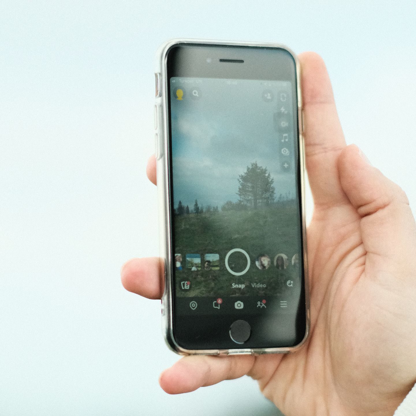 A hand holding a smartphone displaying a photo app screen outdoors in Istanbul, Türkiye.
