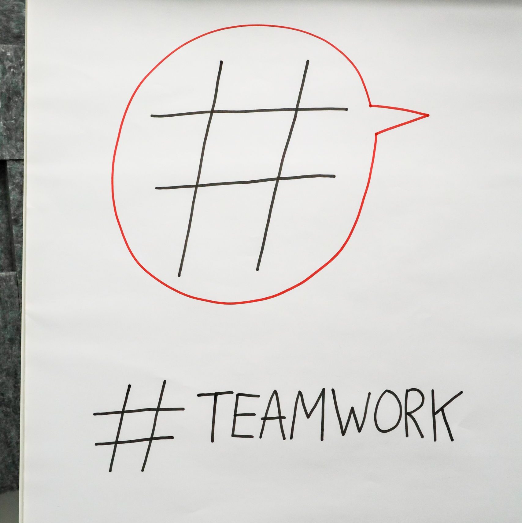A poster in an office setting highlighting teamwork with a hashtag symbol.