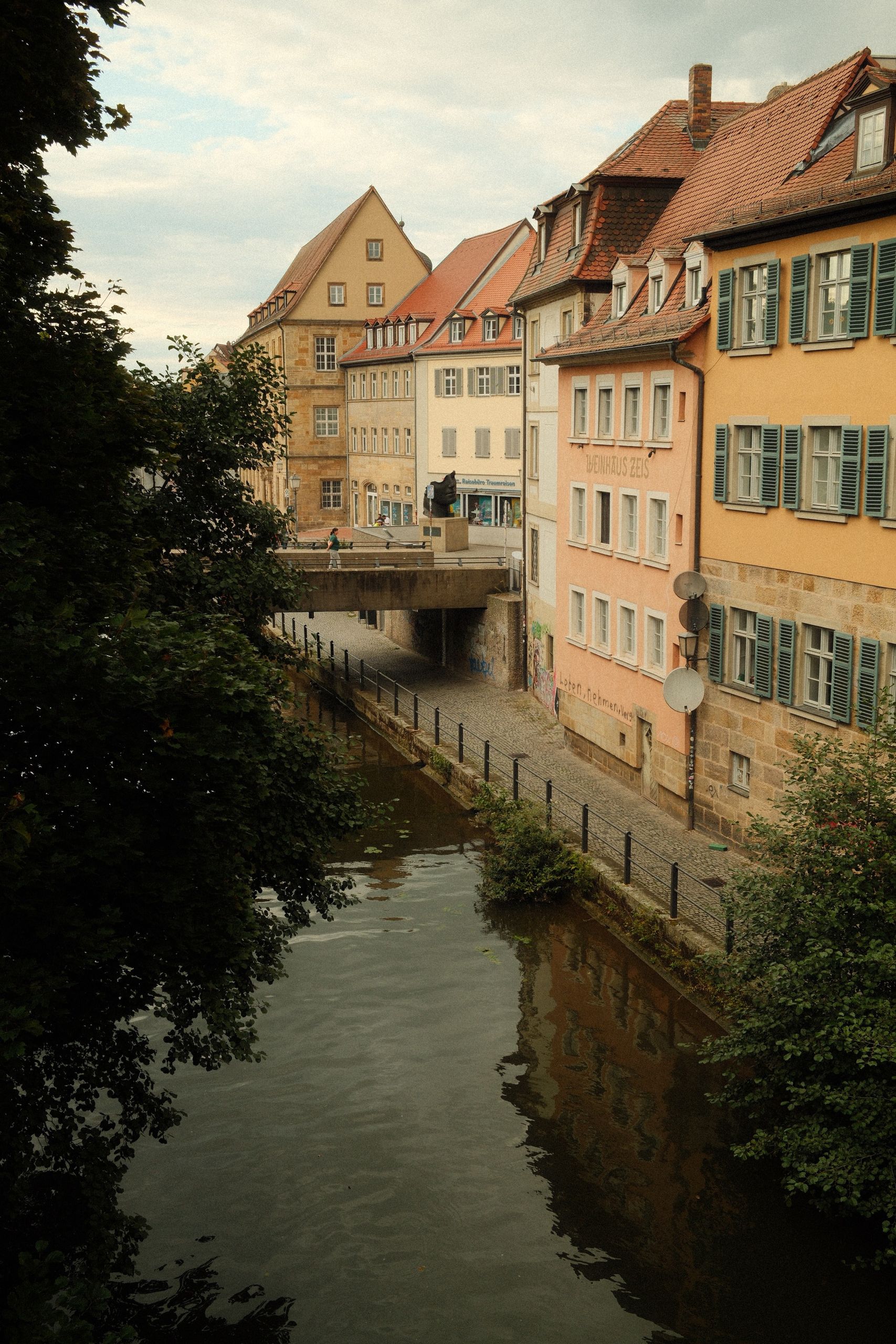 Scenic view of Bamberg's historic buildings lining a tranquil canal on a summer day.